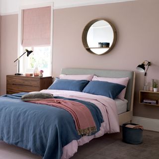 bedroom with pink wall grey bed with cushion and wooden flooring