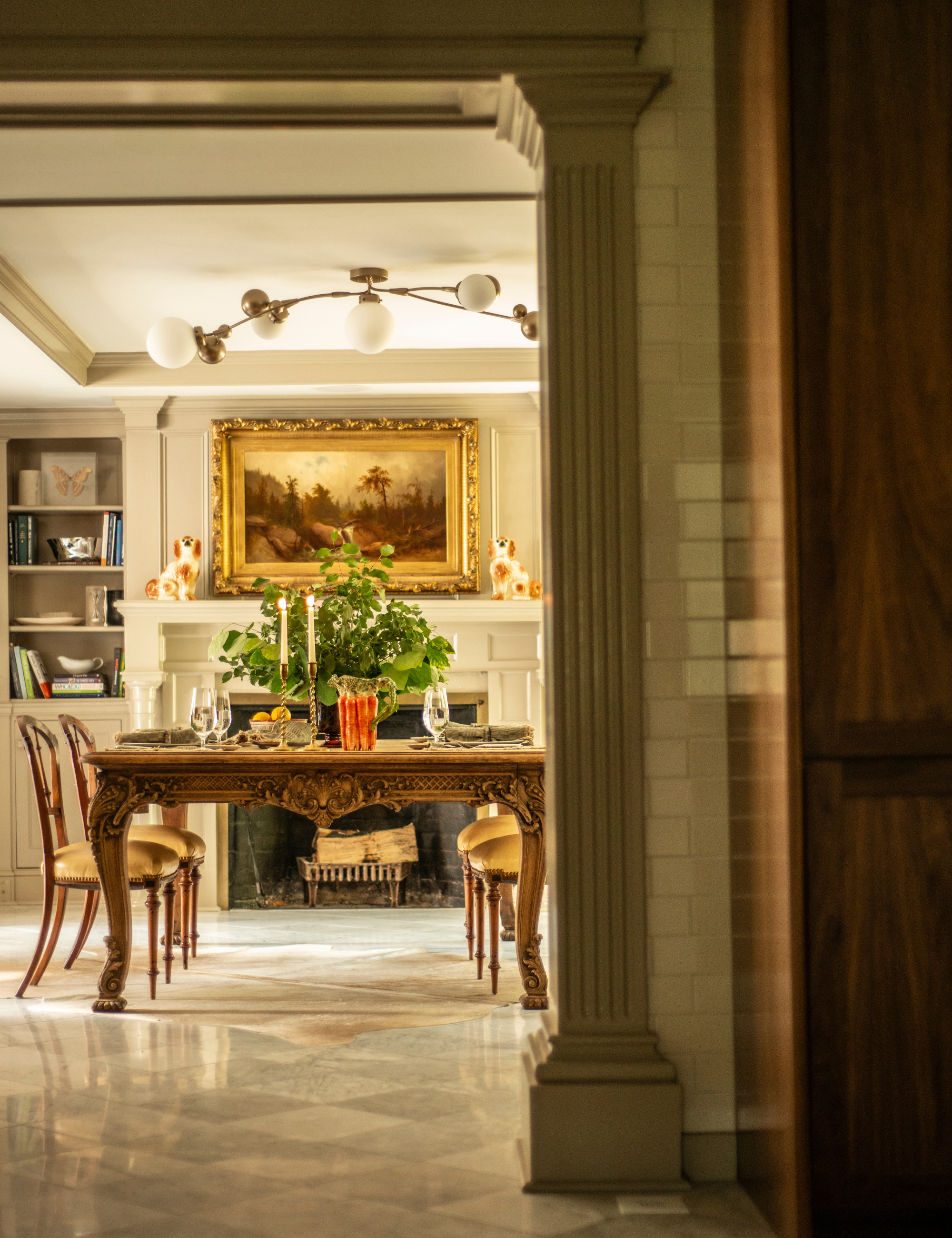 Nicole Fisher-designed dining room juxtaposing a modern orb light chandelier with antique objects