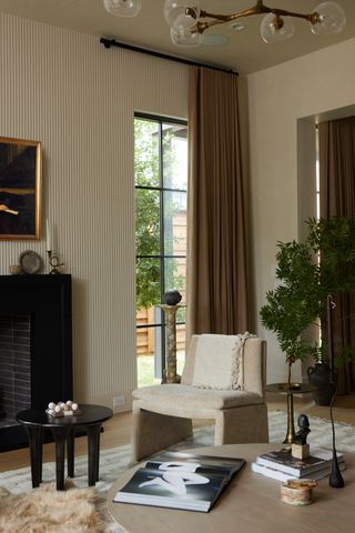 A living space with striped taupe wallpaper and brown drapes