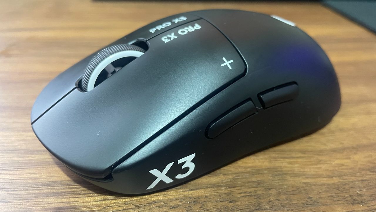 A Logitech G Pro X3 Superstrike gaming mouse on a wooden desk.
