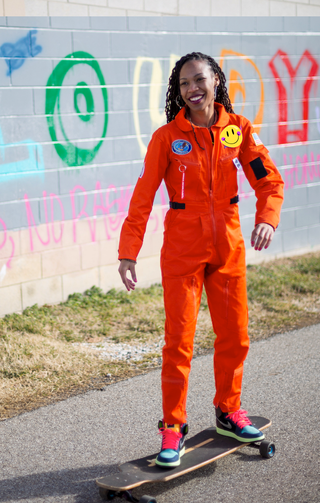 woman in orange jumpsuit in front of a wall with colorful letters