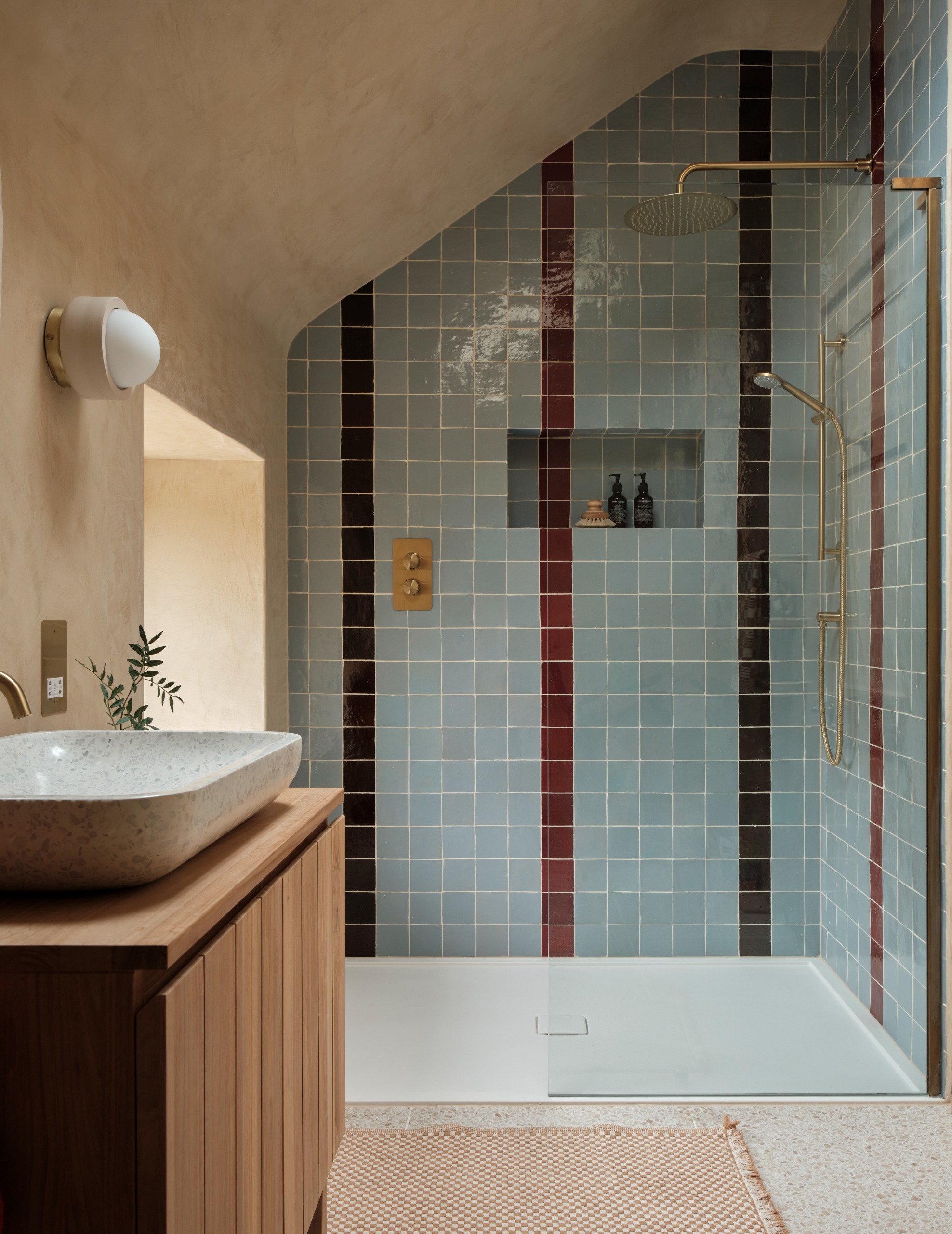 cool, small bathroom with blue and brown striped zellige tiled shower with a glass wall and walk in design