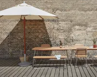 A cream and wood patio umbrella over an outdoor dining table and chairs