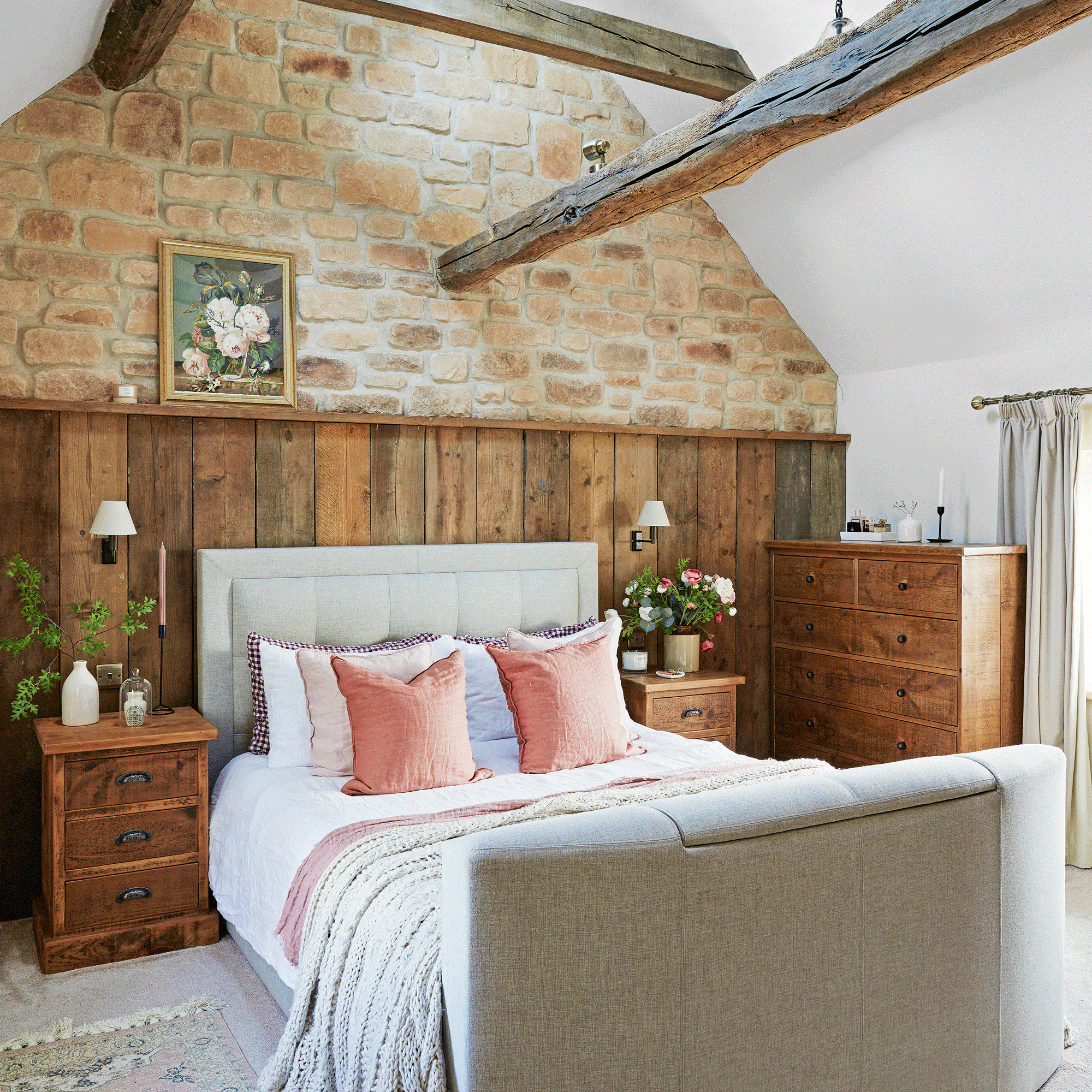 a bedroom with exposed stone wall and wood cladding a bed with layers of bedding and cushions