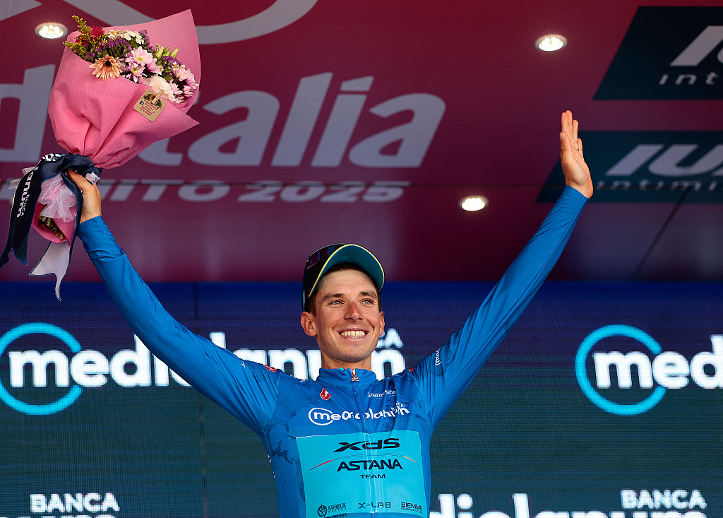 XDS Astana Team's Italian rider Lorenzo Fortunato wearing the best climber's blue jersey (Maglia Azzura) celebrates on the podium after the 18th stage of the 108th Giro d'Italia cycling race of 144kms from Morbegno to Cesano Maderno on May 29, 2025. (Photo by Luca Bettini / AFP)