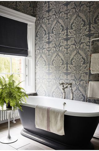 Grey bathroom with patterned wallpaper and roll top bath