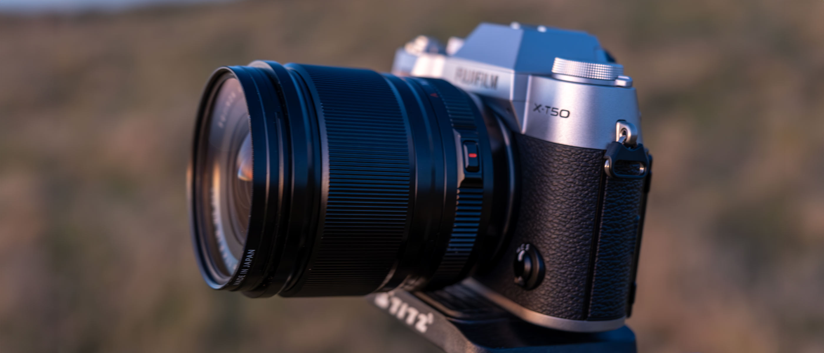 A Fujifilm X-T50 camera on a tripod in a field