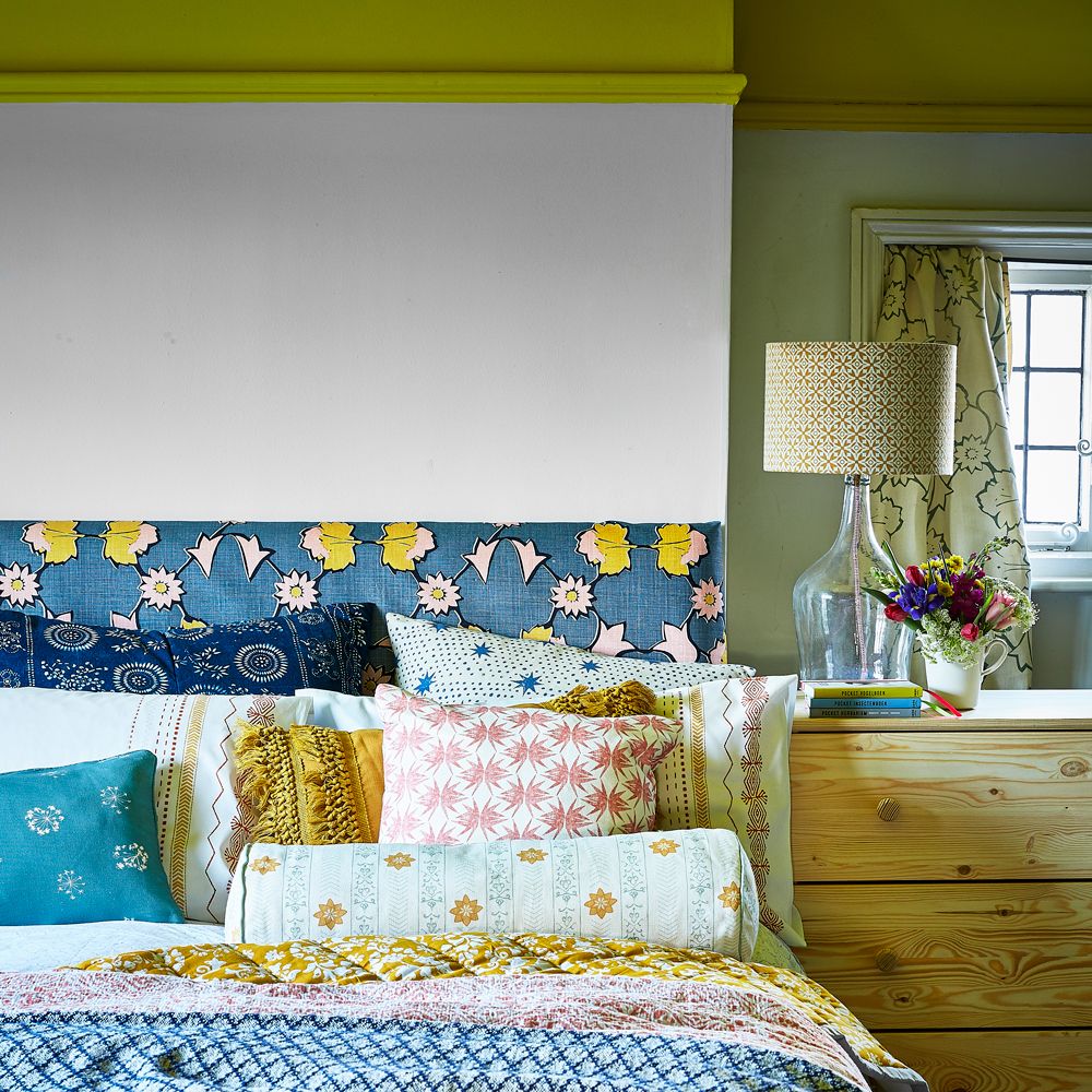 bedroom with printed cushions and lamp on bedside table