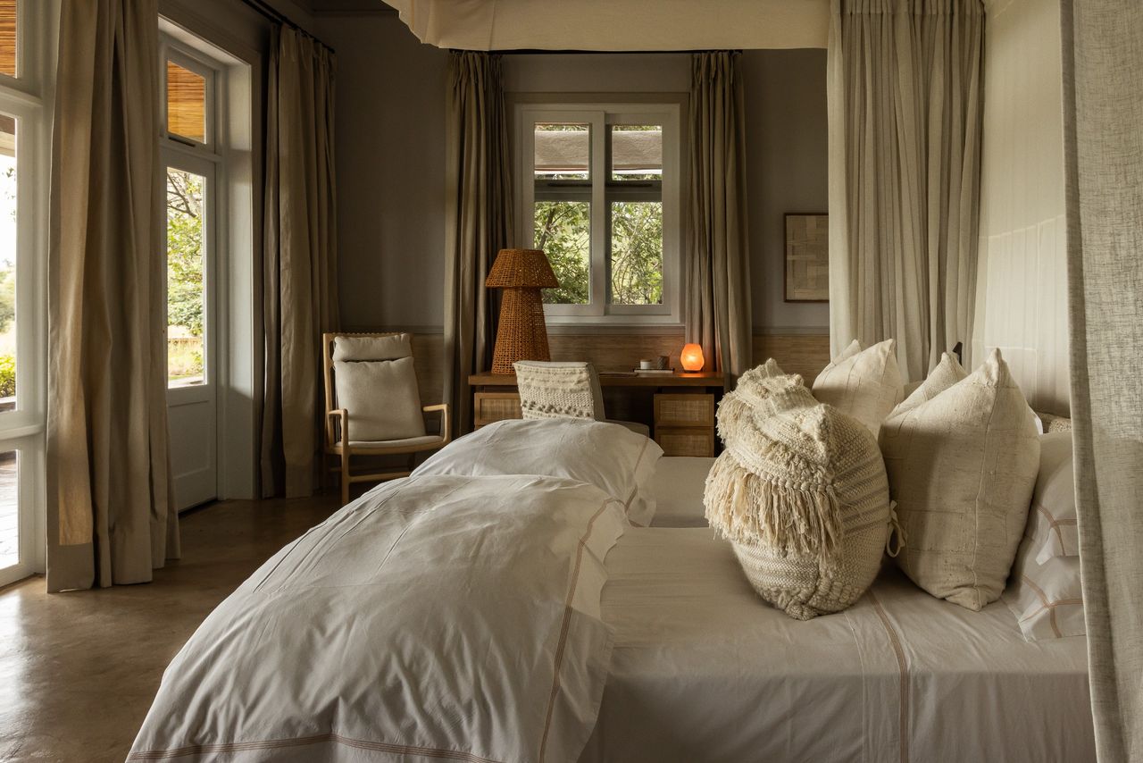 A hotel room featuring twin beds and furniture in neutral tones and rattan