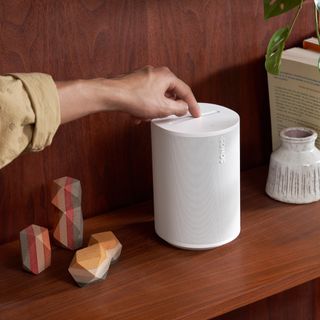 White Sonos wireless speaker on a wooden shelf