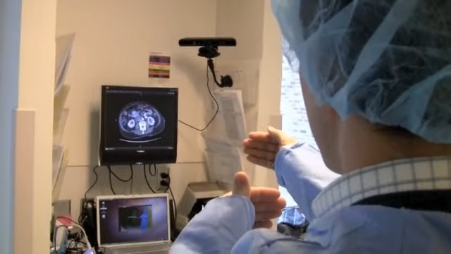 Surgeon gestures in front of image of brain, using an Xbox Kinect to measure movement.