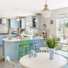 kitchen with hanging lights and vase on table near colourful chairs