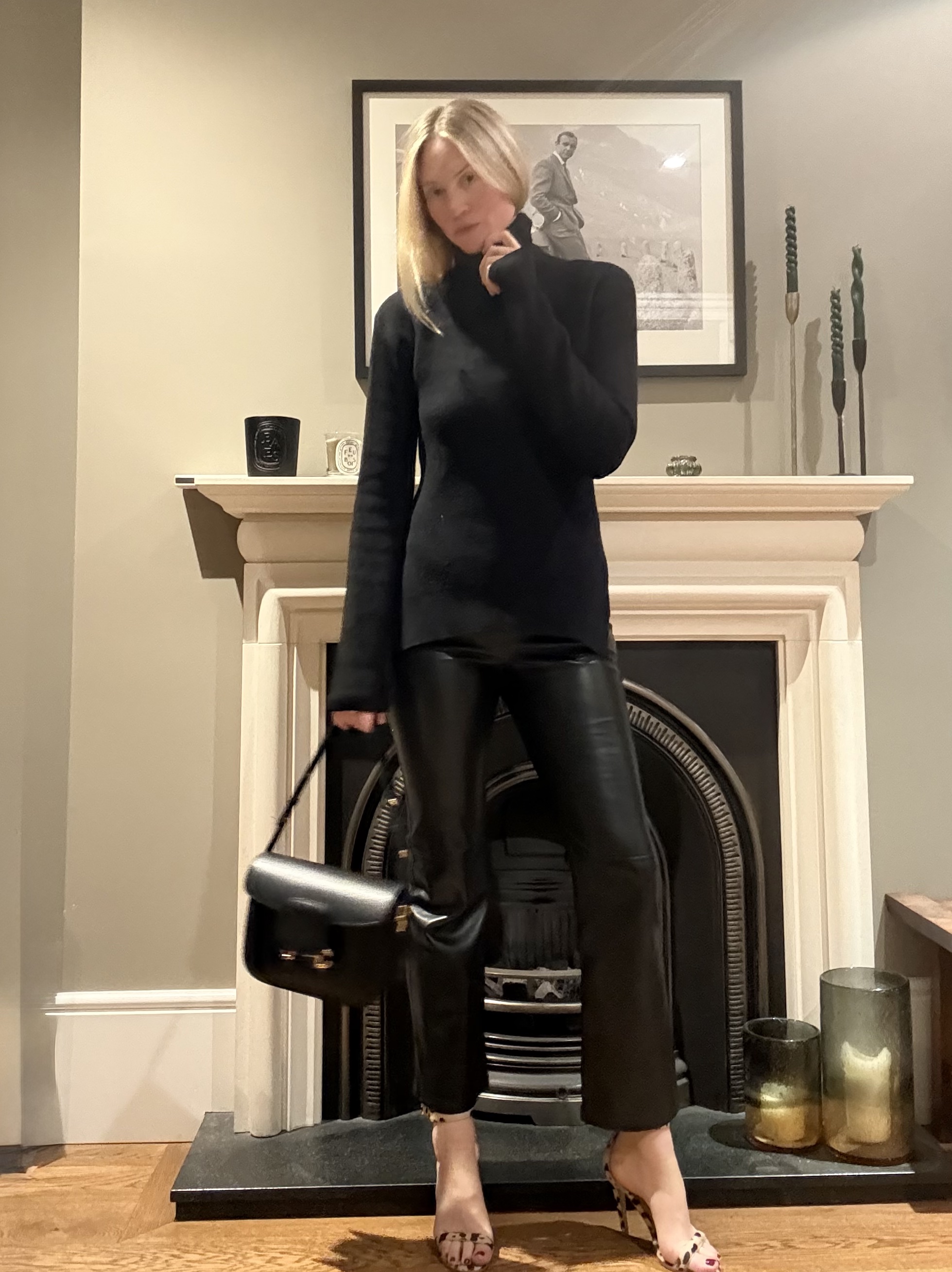 Brooke Ely Danielson wearing a turtleneck sweater and standing in front of a fireplace