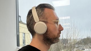 Sony WH-CH520-hörlurar bärs av en man framför ett fönster.