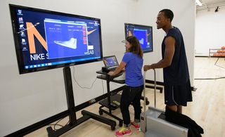 A woman showing a man data about his feet's movement on a large screen
