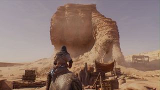 Assassin's Creed Mirage Basim riding horse in desert looking at tall rock ruin 