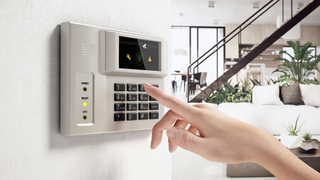 hand reaching towards alarm panel in home