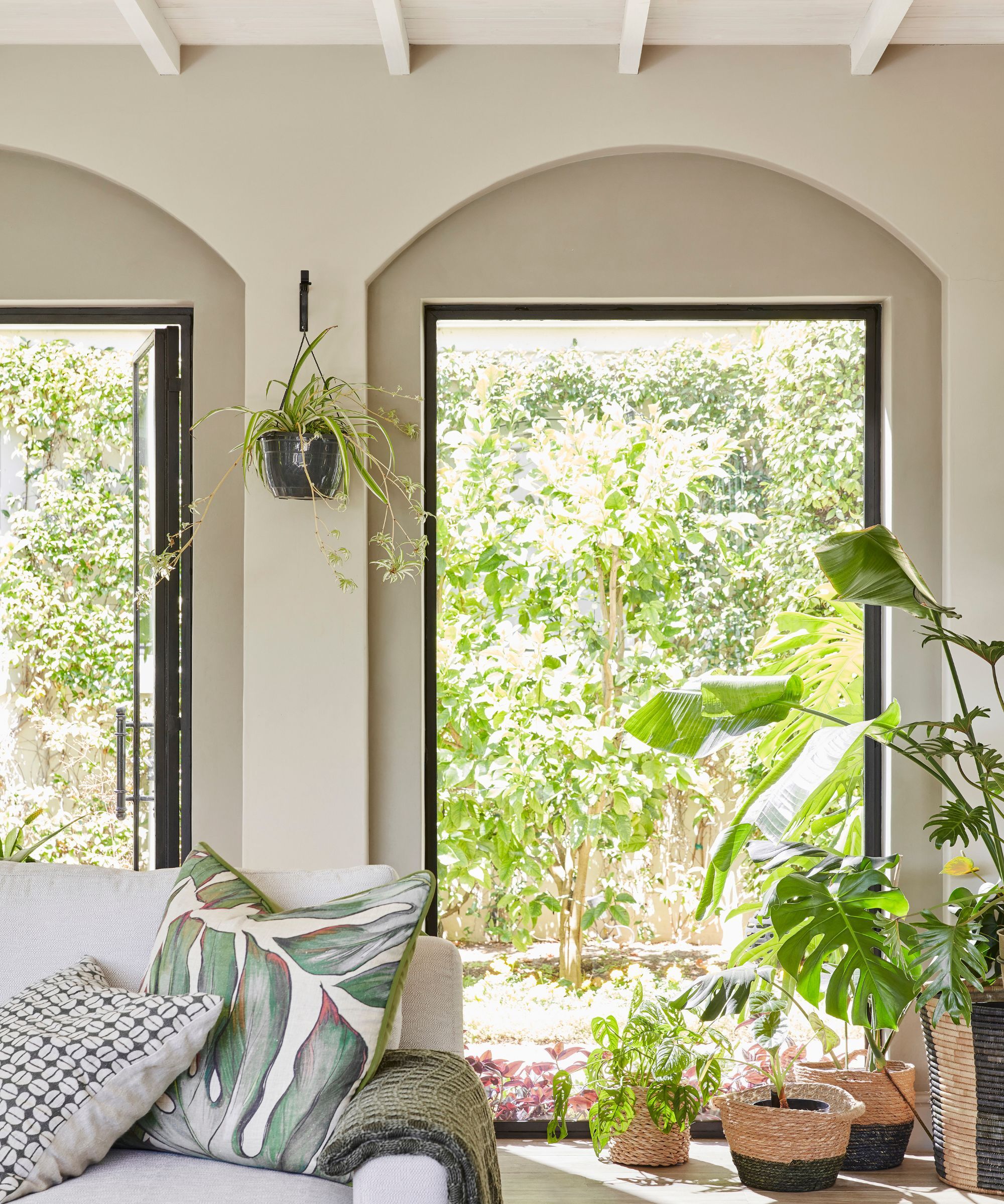 Modern sitting room with neutral walls and large windows to the verdant garden
