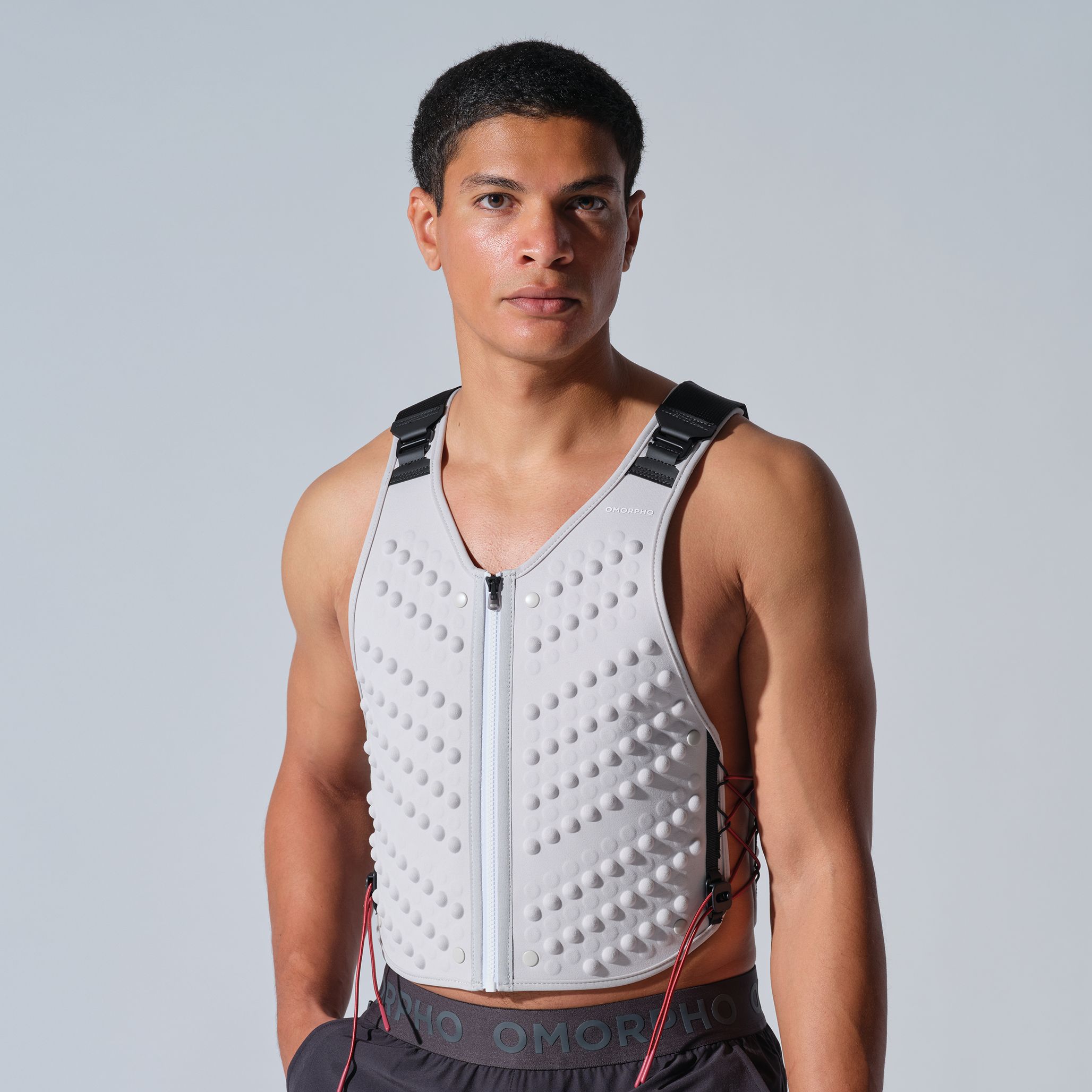 A man wearing a weighted vest against a plain background