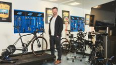Phil Burt standing in his bike fit workshop surrounded by equipment
