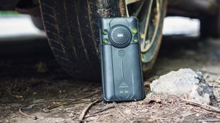 AGM H5 Pro leaning against a car tire on the ground outdoors