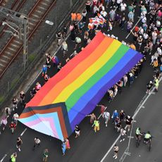In this aerial view, the Progress Pride flag is carried over the Sydney Harbour Bridge as people take part in Pride March on March 05, 2023 in Sydney, Australia.