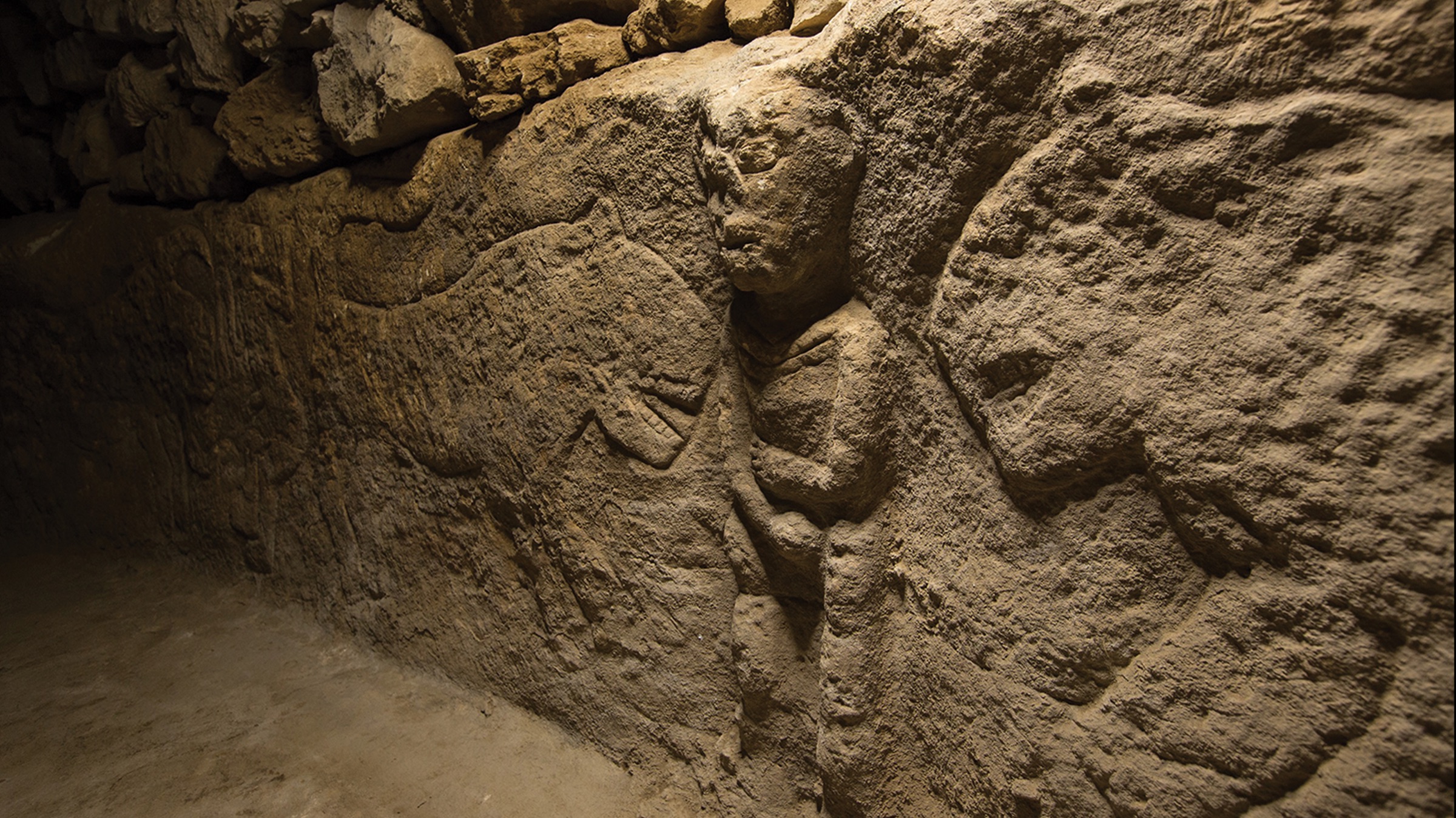 In the carving, the man holding his penis is surrounded by leopards.