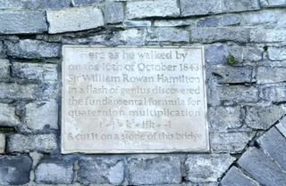 A plaque on a stone bridge that reads "Here as he walked by on the 16th of October 1843, Sir William Rowan Hamilton in a flash of genius discovered the fundamental formula for quaternion multiplication, i^2=j^2=k^2=ijk=-1, and cut it on a stone of this bridge"