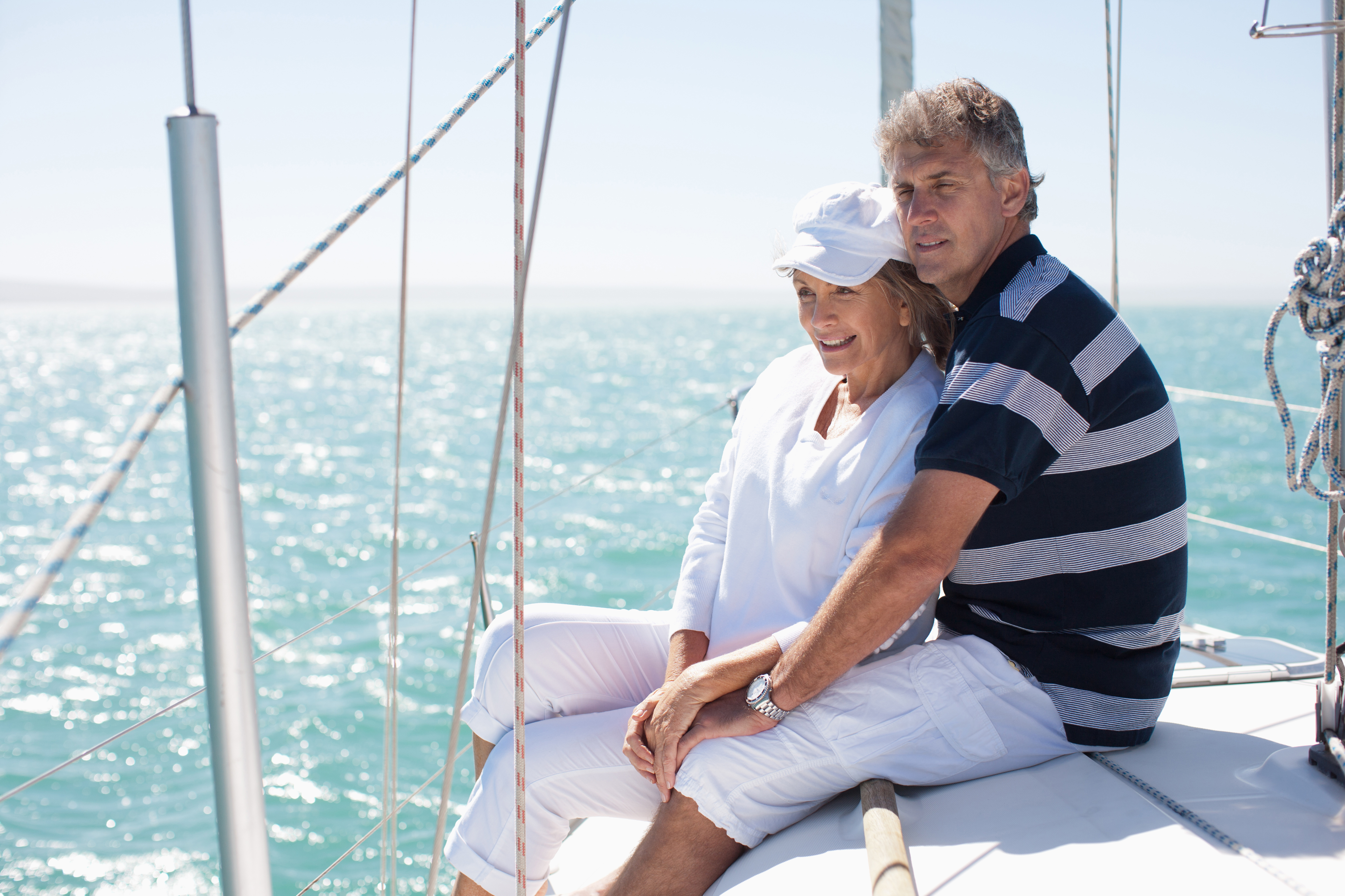 A mature couple sits on a sailboat.