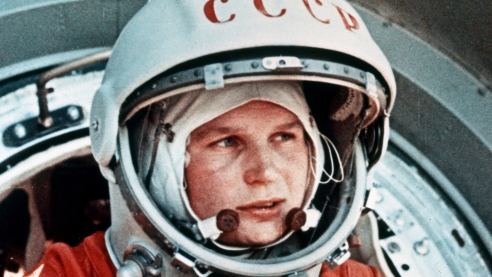 A woman wears a helmet and an orange outfit