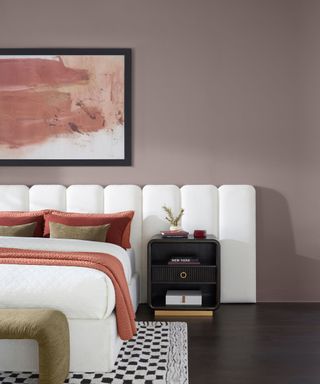 bedroom with purple walls, white headboard, pink artwork and cozy textiles