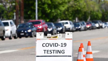 Drivers in their vehicles wait in a long line at a coronavirus testing site in Los Angeles, California on June 10, 2020