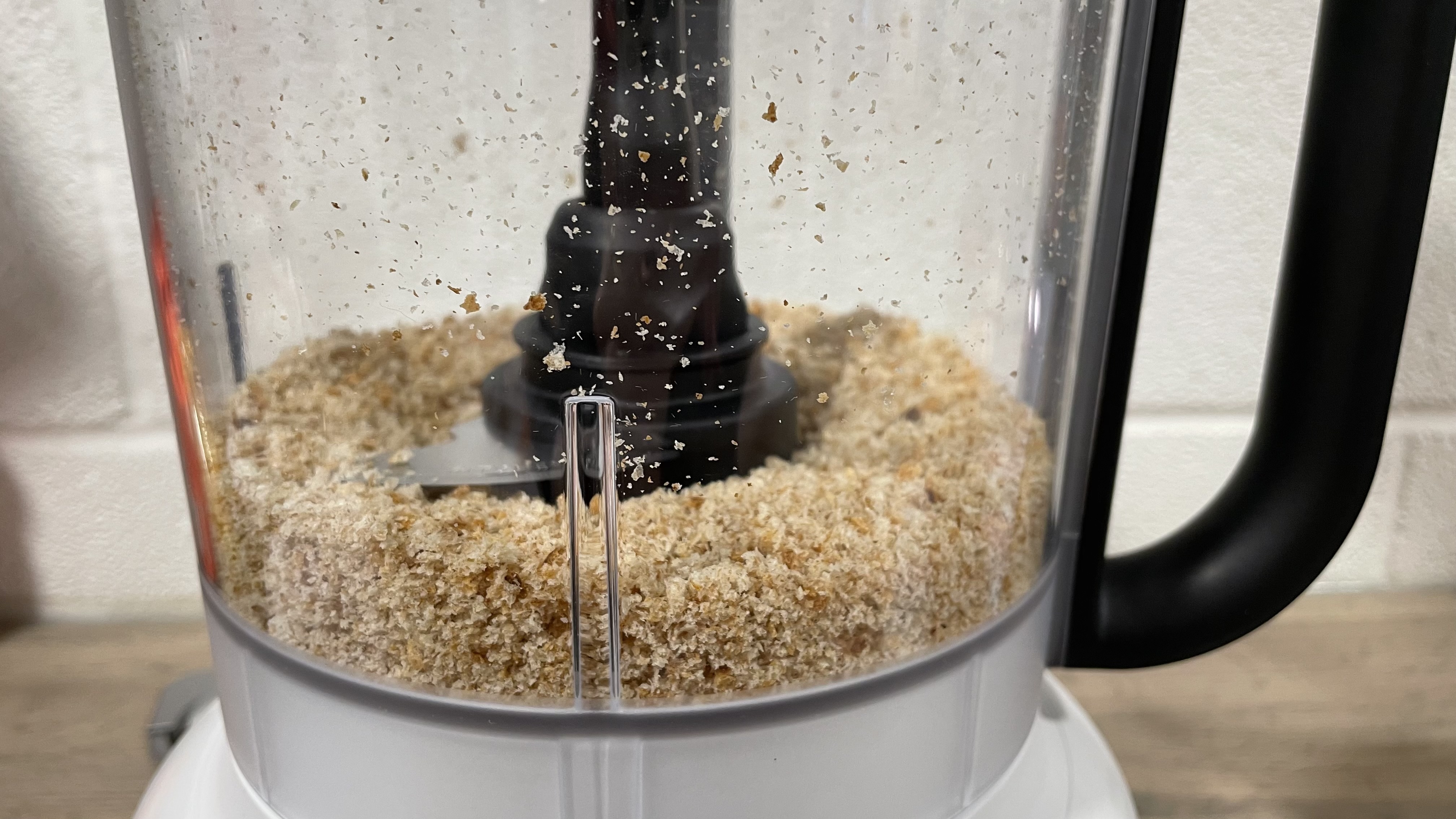 A close up of breadcrumbs in the work bowl of the KitchenAid Mini Food Chopper.