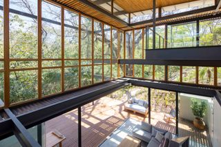 Interior of the jungle house with glass windows and grey sofa