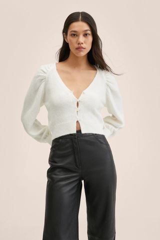 woman wearing a white cropped sweater from Mango's sale collection 2022. 