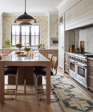 Warm-colored kitchen with wooden dining table, large stove and yellow tone rug