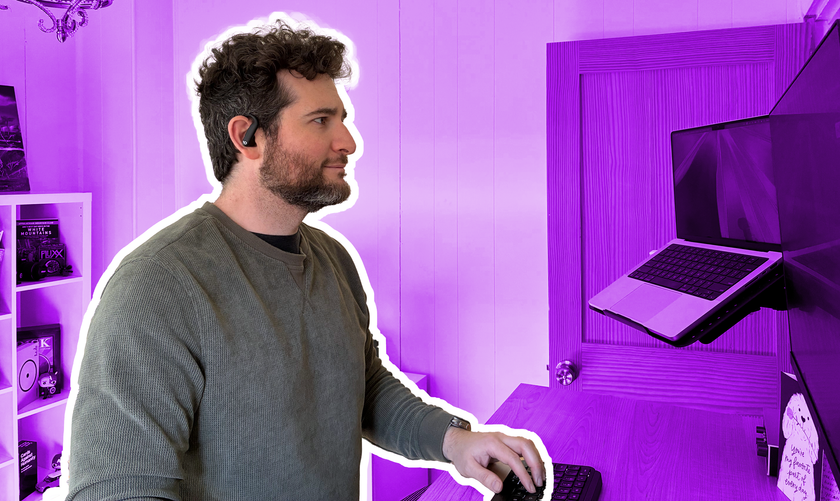 Photo illustration of a man standing at a desk wearing the Apple Powerbeats Pro 2 earbuds.