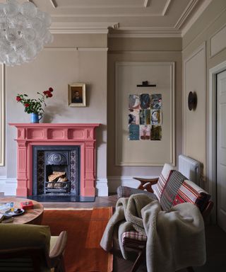winter decor ideas, living with neutral stone walls, panels with artwork, pink fire surround, rug, retro couch with faux fur throw, sculptural glass pendant