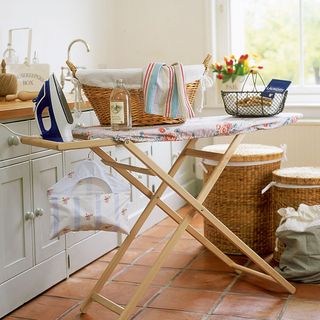 room with ironing board and cane basket