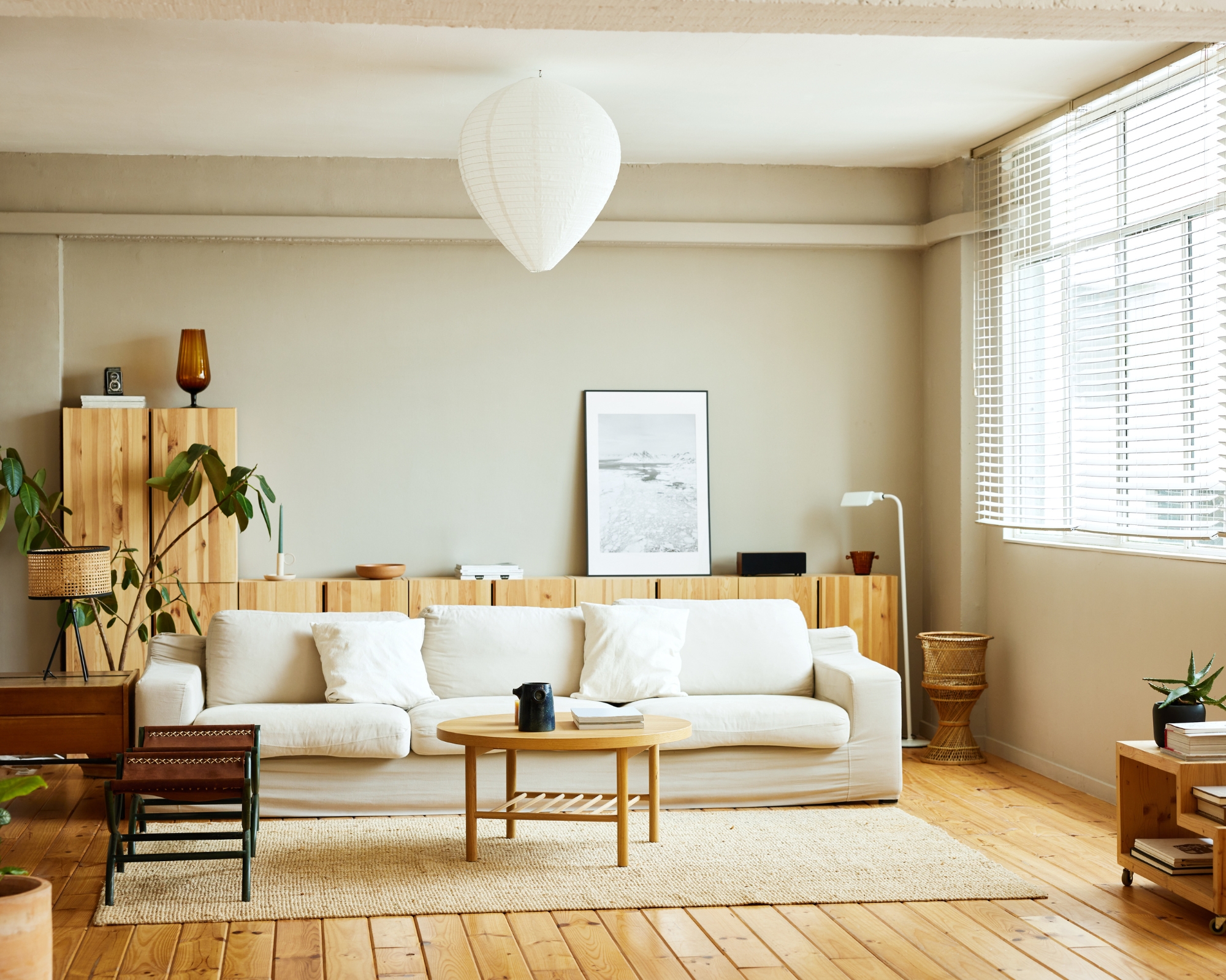 Modern bright living room with white sofa, wooden floor and wooden cabinets