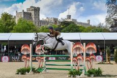 Eleanor Hirst riding Noble Gladiator jumping a fence in the working hunter class in the main arena at Royal Windsor with the stands and the castle behind them.