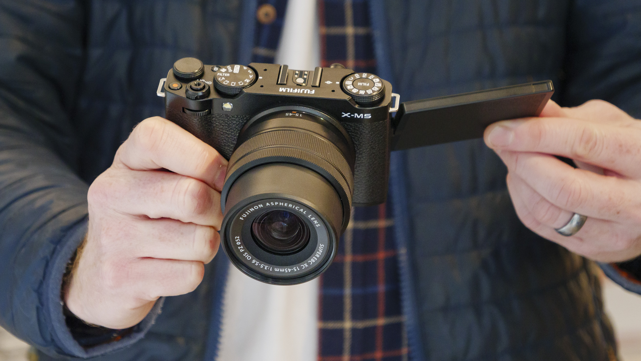 Fujifilm X-M5 camera with 15-45mm lens, in the hand, with screen flipped out