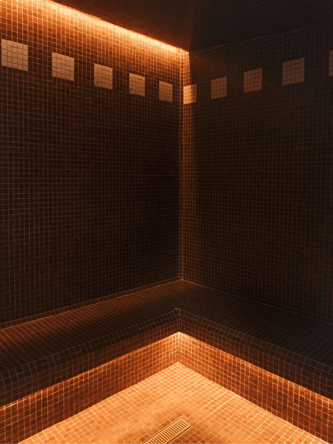 Two angles of a sauna: wooden benches and a bucket with water and ladel