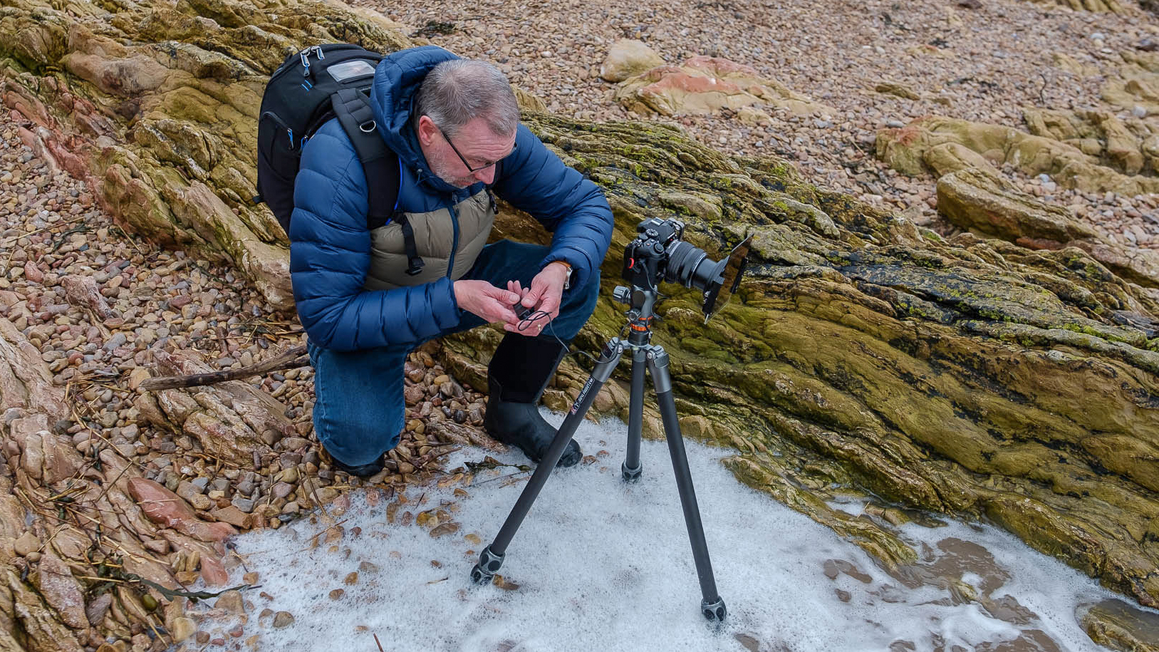 Olympus OM-D E-M1 Mark III being used by a photographer outdoors, on a tripod with an ND filter system