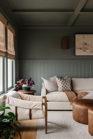 A living room with cream sofas, and dark green walls