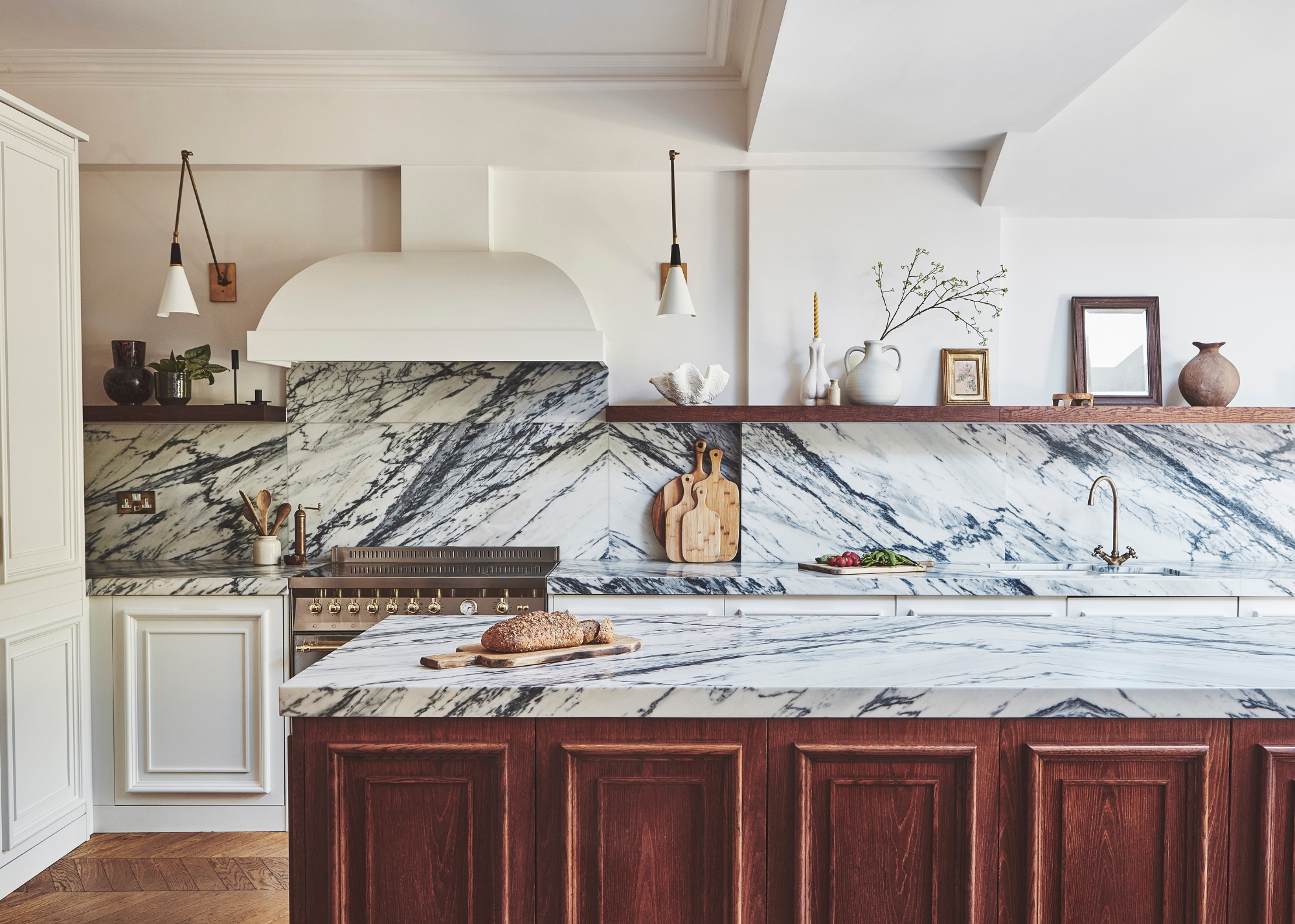 A traditional dark wood and white kitchen with dramatic marble veining in the white countertop and open shelving along the back