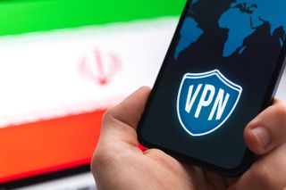 Hand with mobile phone and VPN application in front of the Iran flag