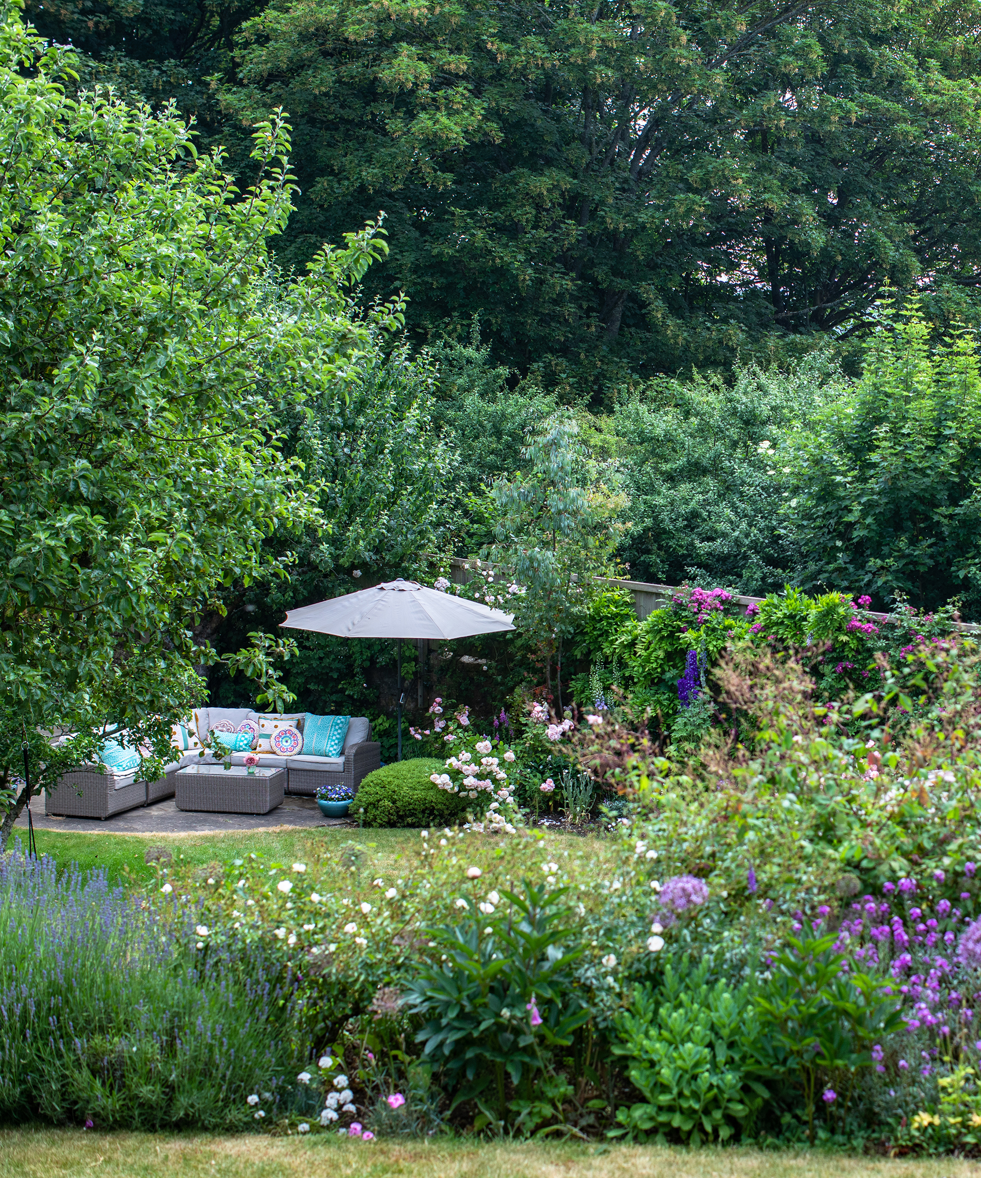 view down a garden with flower beds and outdoor seating area with parasol