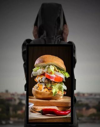 A burger and hot pepper in stunning detail is presented on a 21.5-inch digital signage display on a backpack.