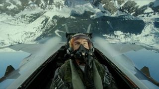 Tom Cruise in a plane's cockpit flying over mountains